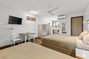 Broome Time Resort في بروم: غرفة فندقية تحتوي على سريرين ومكتب وتلفزيون