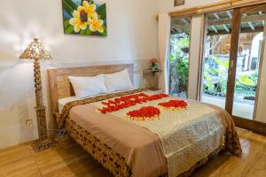 Un dormitorio con una cama con flores rojas. en Uma Shanty Homestay, en Karangasem