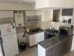 eine kleine Küche mit Kühlschrank und Spüle in der Unterkunft Sueños del Sur, moderno departamento in Comodoro Rivadavia