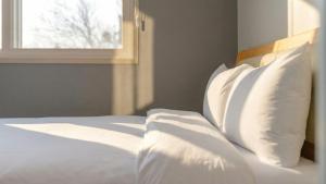 泰安Taean Blueisland Pool villa的一间卧室，配有一张带白色枕头的床和一扇窗户