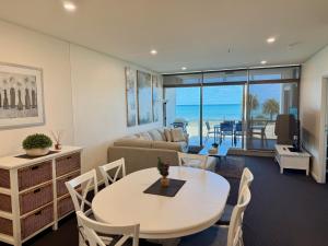 ein Wohnzimmer mit einem Tisch und einem Sofa in der Unterkunft Frontage Apartments- 3Bedroom Central Seaview Escape in Victor Harbor