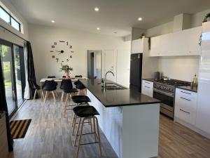 a kitchen with white cabinets and a large clock on the wall at Playground Fun on Town Doorstep! in Ohakune