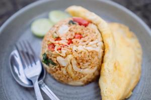 a sandwich with rice and vegetables on a plate with a fork at The Caldera Villas in Kubupenlokan