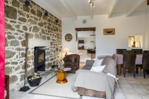 Una sala de estar con chimenea de piedra y un sofá. en La fringante, en Pleubian