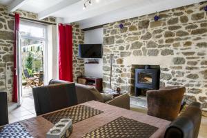 Una sala de estar con una pared de piedra con una mesa y una chimenea. en La fringante, en Pleubian