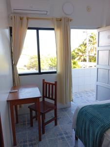 a bedroom with a desk and a bed and a window at Hostal Insular in Puerto Villamil