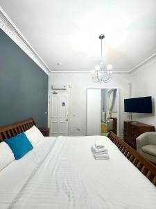 um quarto com uma grande cama branca e um lustre em West Coates Mansion em Edinburgo