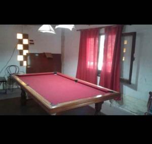 tavolo da biliardo in una stanza con tenda rossa di Rodolfo cabaña a Cosquín