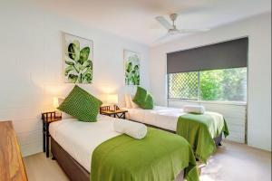 a bedroom with two beds with green sheets and a window at 2-Bedroom Charm near Mater Hospital Pimlico Townsville in Aitkenvale