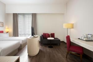 Habitación de hotel con cama, TV y silla en Amandaru Hotel Pekalongan, en Pekalongan