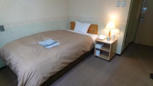 um quarto com uma cama grande e uma mesa de cabeceira com um telefone em Hotel Himeji Hills em Himeji