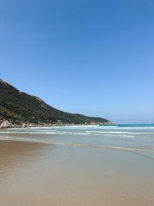 a beach with some waves in the ocean at Wombat Pavilion in Yanakie +3 photos