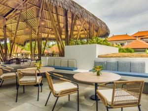 eine Außenterrasse mit Tischen und Stühlen sowie ein Gebäude in der Unterkunft eL Hotel & Resort Bali Sanur in Sanur