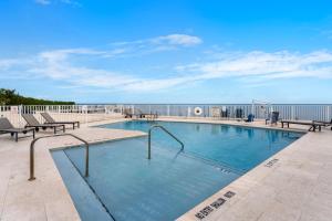 ein Pool mit Bänken und das Meer im Hintergrund in der Unterkunft Oceanfront Luxury w/Speakeasy Lounge, Dock & Pool in Islamorada