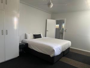 a white bedroom with a bed and a closet at 80 Tarcutta St in Wagga Wagga