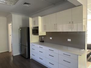 a kitchen with white cabinets and a black refrigerator at 80 Tarcutta St in Wagga Wagga