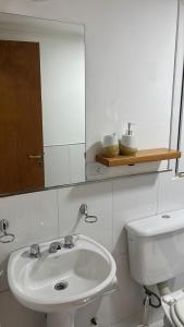 een badkamer met een witte wastafel en een spiegel bij Líbano flat in El Bolsón +5 foto's