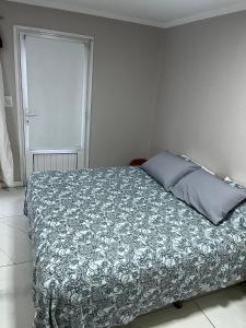 een slaapkamer met een bed met een deken en een raam bij Líbano flat in El Bolsón