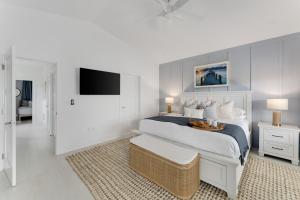 a white bedroom with a large bed and a tv at Ocean Views with Secret Speakeasy BBQ Patio Dock Pool 3br with Private Bathrooms in Islamorada +32 photos