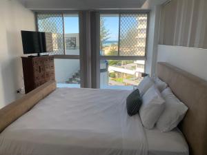 a bedroom with a bed with a television and windows at Ocean Plaza Resort in Gold Coast +44 photos