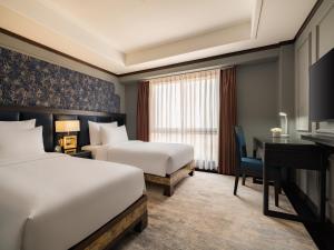 a hotel room with two beds and a desk at Hanoi Solis Hotel in Hanoi