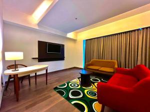 a living room with a red couch and a tv at Amandaru Hotel Pekalongan in Pekalongan +7 photos