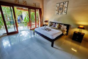 a bedroom with a bed in a room with windows at Matra Bali Guesthouse in Canggu