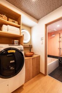 une buanderie avec une machine à laver et une baignoire dans l'établissement Machiya Izumi higashiyama, à Kyoto