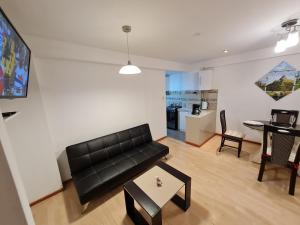 een woonkamer met een zwarte bank en een tafel bij WASI in Cuzco