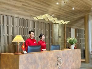 2 persone in piedi presso la reception con computer portatili di Túi Ba Gang Central Hotel a Da Lat