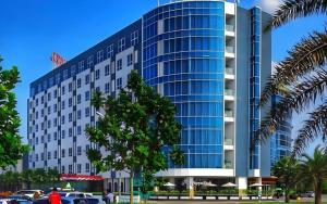 Un gran edificio de cristal con coches aparcados delante. en Wing Hotel Kualanamu Airport, en Kampungbesar