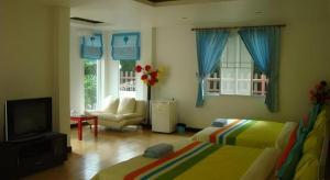 a bedroom with two beds and a tv and a couch at Sea Beach Koh Larn 1 in Ko Larn