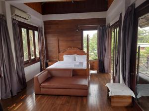 a bedroom with a bed and a couch and windows at Thao’s Villa in Ho Chi Minh City