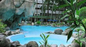 Una gran piscina en un complejo turístico con una pared de roca. en Danau Toba Hotel International, en Medan