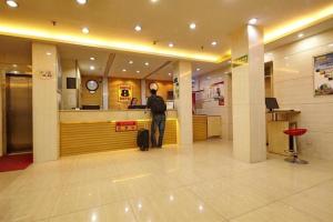 a man standing in front of a counter in an airport at Super 8 Hotel Jinan Railway Station Square in Jinan