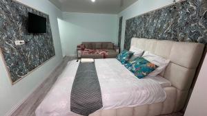 a bedroom with a bed with a couch and a television at Shymkent plaza 3 in Shymkent