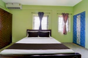 Cama en habitación con paredes y ventanas verdes en Collection O MKU Madurai Formerly Mpl Elite, en Samayanallūr 20 fotos más