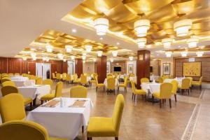 a dining room with white tables and yellow chairs at Shaoxing Yintai Hotel in Shaoxing