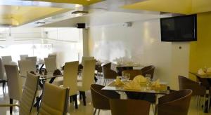 uma sala de jantar com mesas e cadeiras e uma TV de tela plana em The Grande Suites em Surigao
