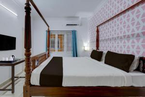 Un dormitorio con una cama grande y un escritorio. en Collection O Sunrise Point Serenity Beach Formerly White Lotus Residency, en Kottakupam