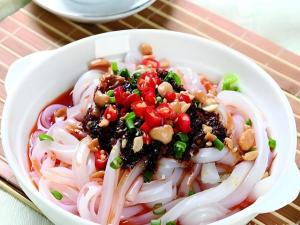 a white bowl of food with noodles and vegetables at Mount Emei Fulin Hotel in Baoguosi