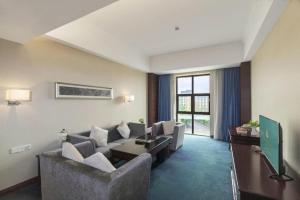ein Wohnzimmer mit Sofa und Fernseher in der Unterkunft Shenzhen Jin Mao Yuan Hotel in Sanjiaolou