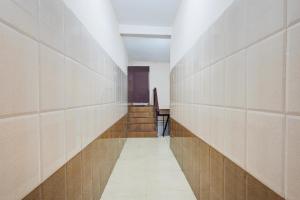 a hallway with white tile walls and stairs at Hotel O Rock Beachview Pondicherry Formerly Varsha Residency in Puducherry