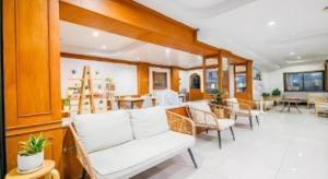 a living room with a white couch and chairs at Grand PL Ville Hotel in Phatthalung