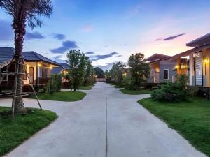 a driveway leading to a house with a palm tree at Tong Hotel in Ban Nong Chik