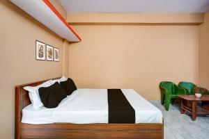 a bedroom with a bed and two green chairs at Hotel O Bidadi Railway Junction Bangalore Formerly Ejalla in Bidadi +22 photos