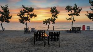 um grupo de cadeiras sentadas na praia ao pôr do sol em Gyeongju Luna Piena Poolvilla em Gyeongju