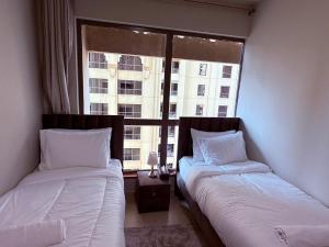 twee bedden in een kamer met een raam bij Nuchi Jbr Hostel in Dubai