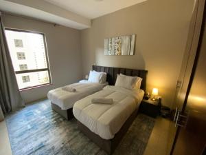 een hotelkamer met twee bedden en een raam bij Nuchi Jbr Hostel in Dubai