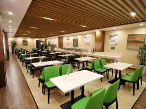 a dining room with tables and green chairs at GreenTree Inn Xuancheng Jingxian Wannan First Street Express Hotel in Jingxian